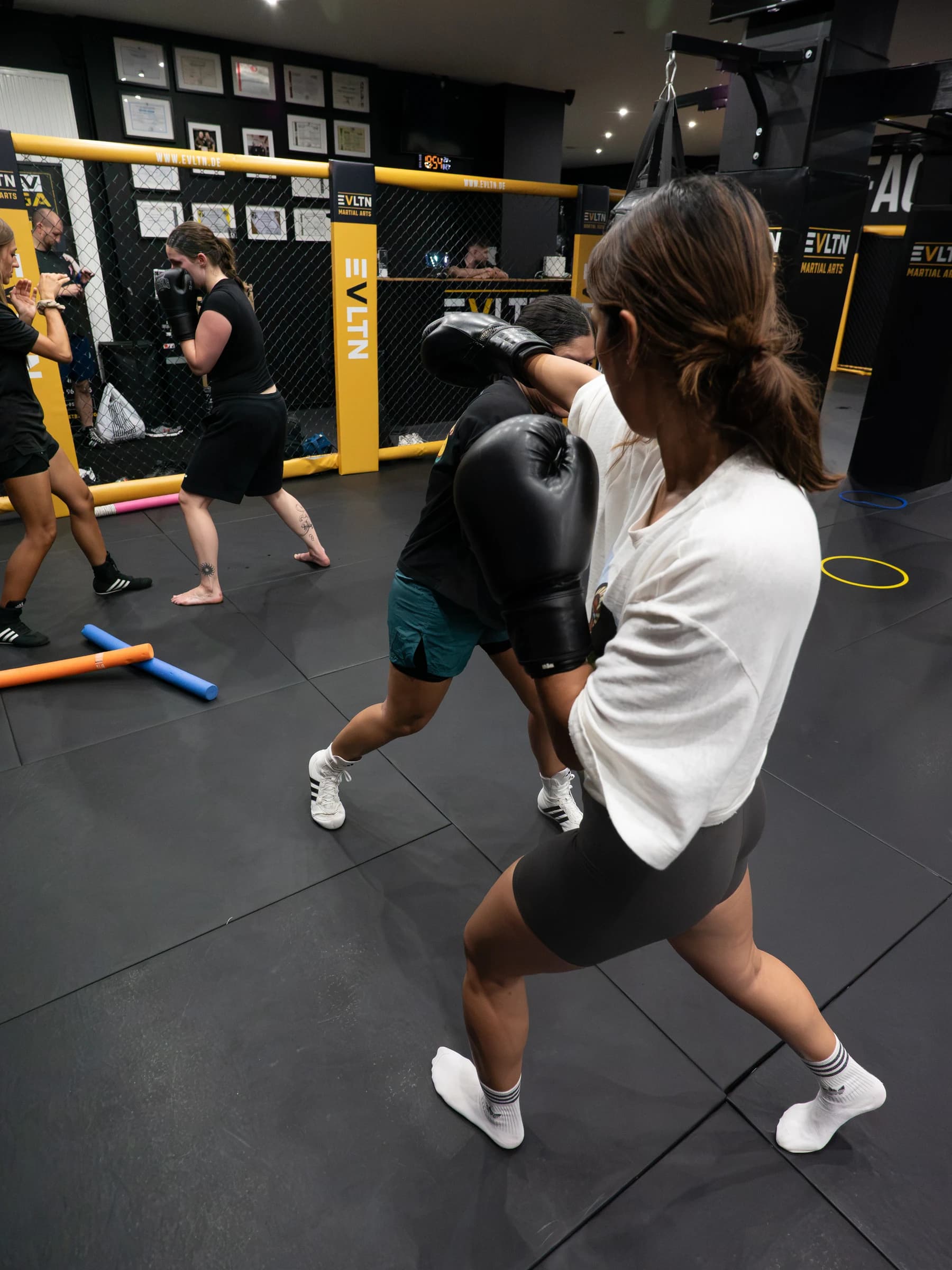 Boxerinnen üben Schläge und Ausweichbewegungen beim Partnertraining im EVLTN Gym